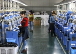 4月29日，新疆库车弘扬针织有限公司的工人在全自动制袜机上整理棉袜。 - 招商发展局